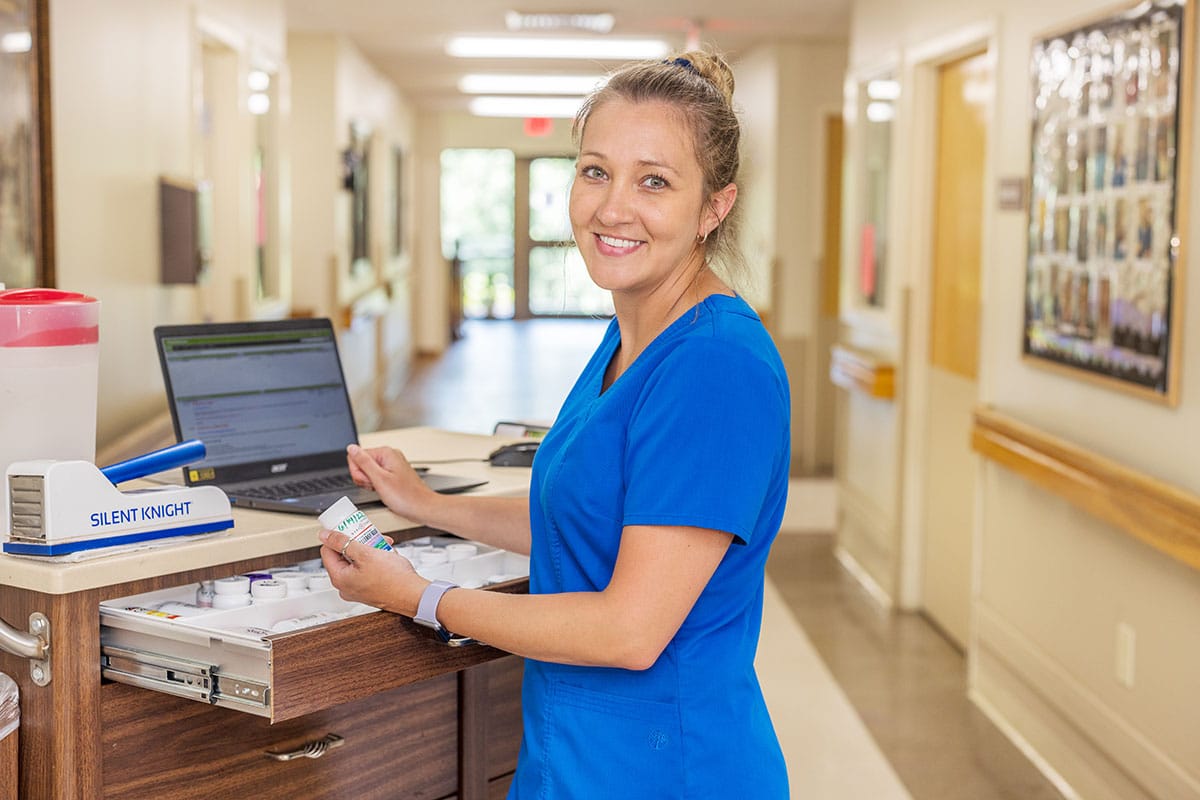 A nurse at a nurse's cart in the hallway at the Piedmont Post Acute facility